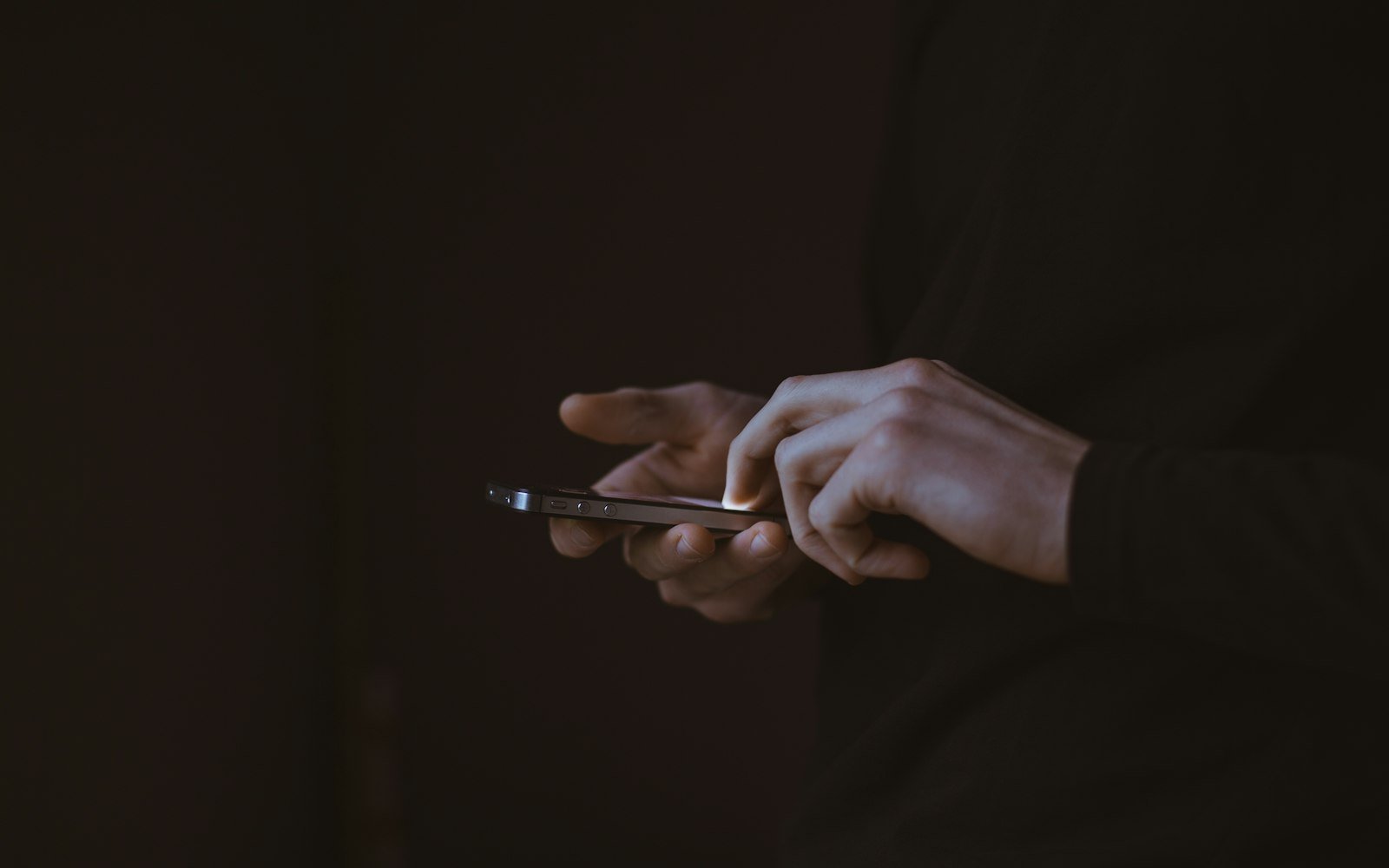 Hands holding a phone in a dark room