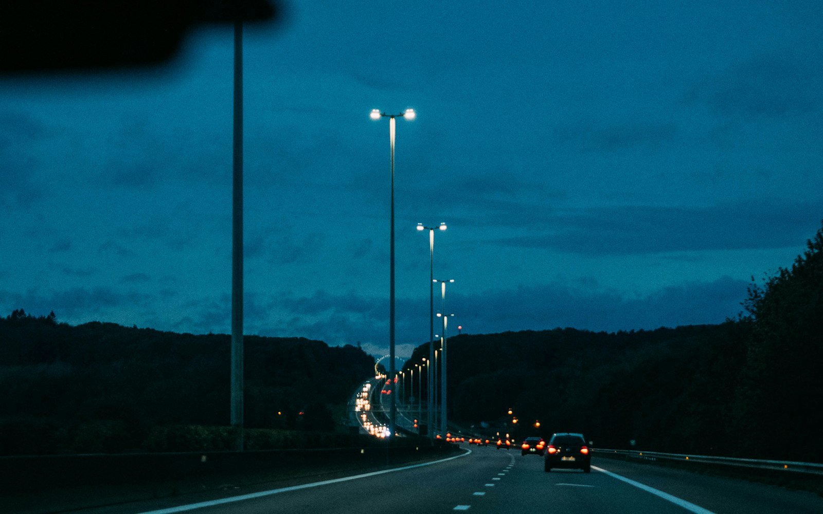 Highway at dusk with cars and tall light poles