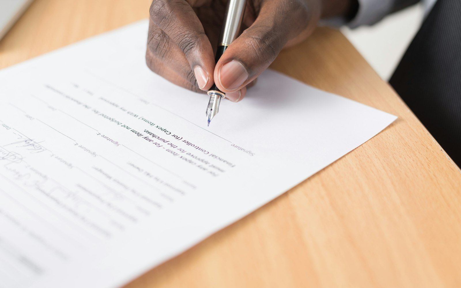 Person signing a document at a desk