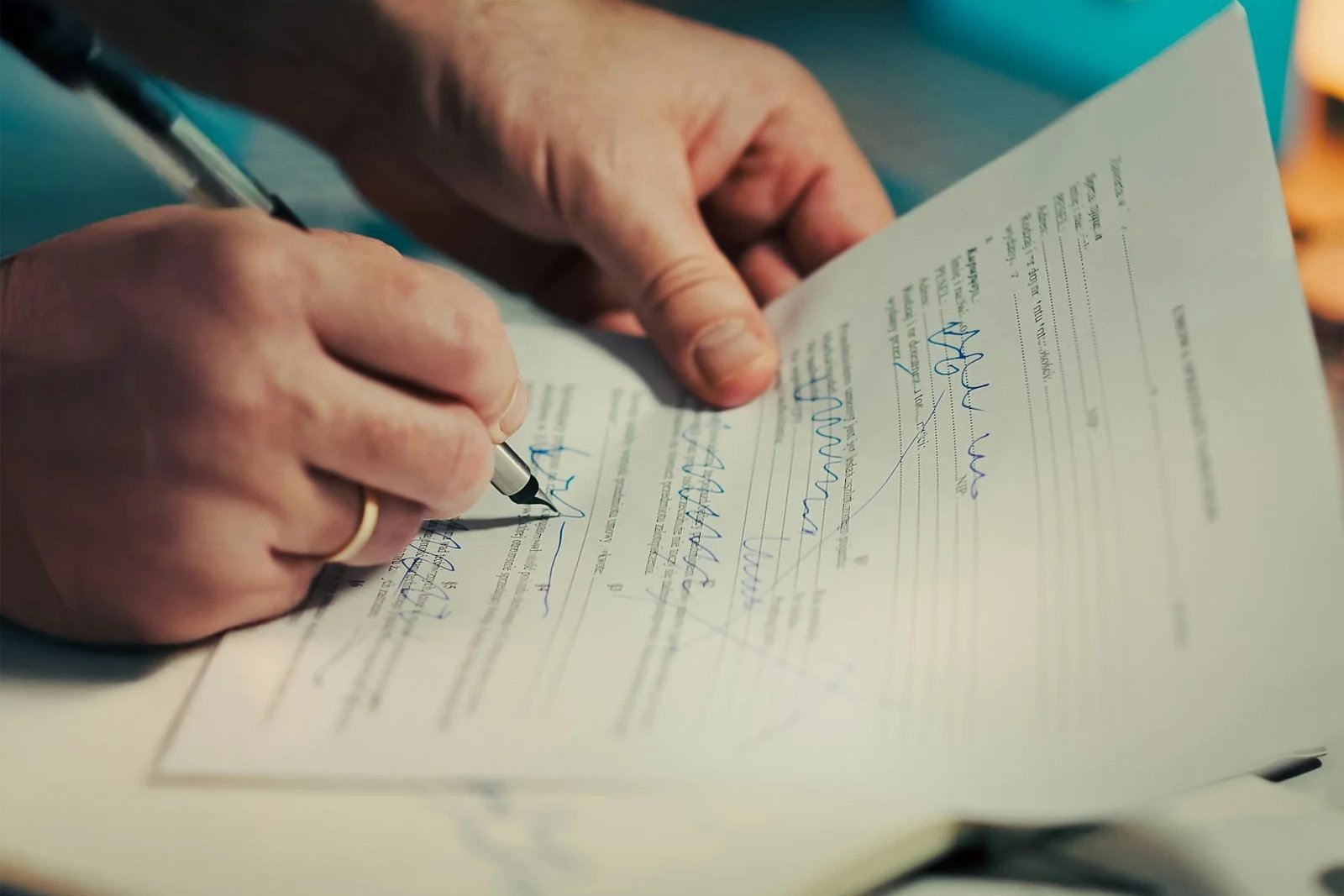 A person signing a printed agreement with a pen