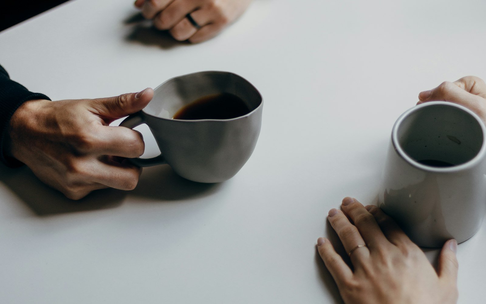 Two people talking at a table with cups of coffee