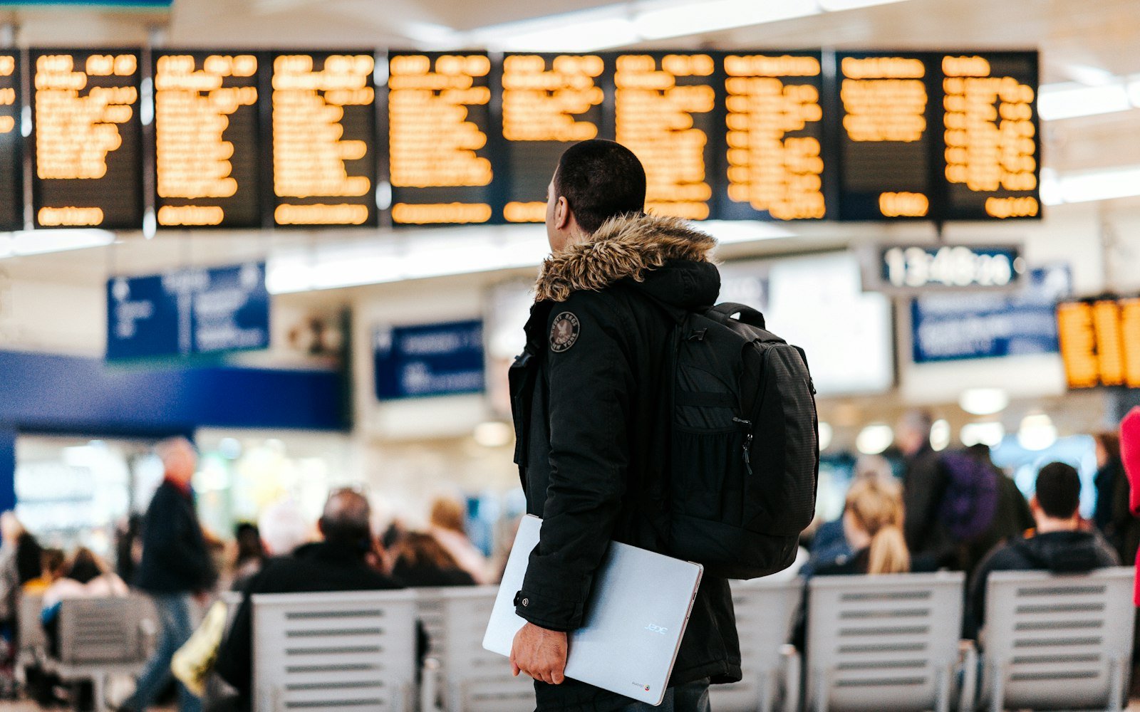 A traveller looking at an airport departures board, seen from behind